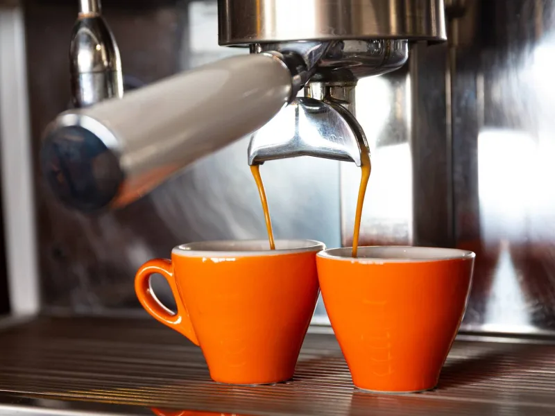 Deux cafés coulent dans des tasses orange